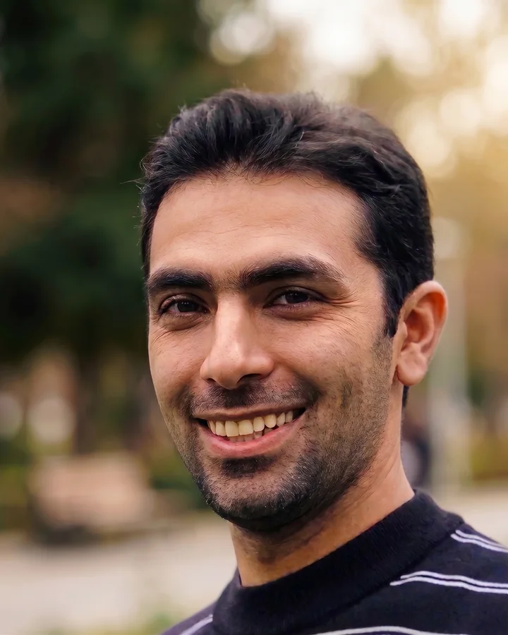 Ehsan Jalilvand, smiling, outdoors among trees.